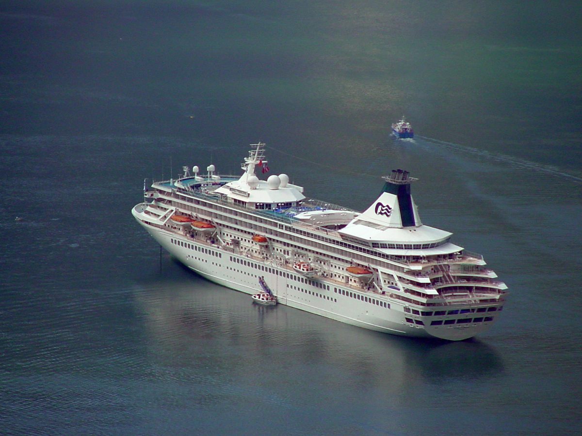 Large cruise ship anchored in the Geirangerfjord below steep mountain walls