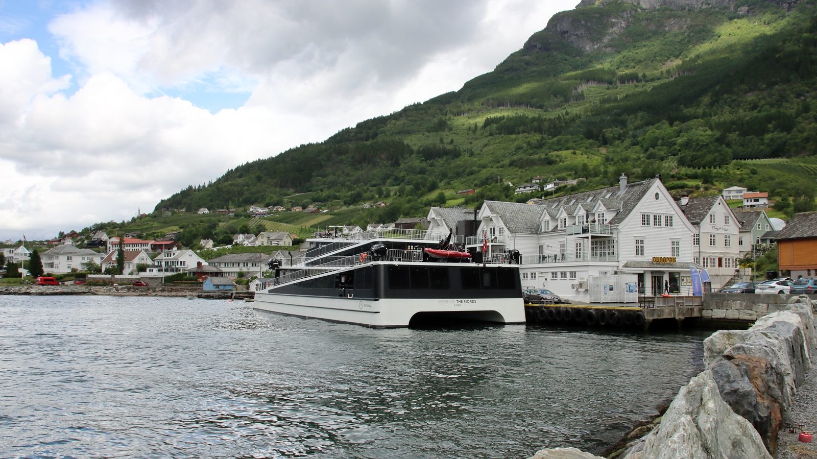 An express passenger boat gliding up a narrow Norwegian fjord