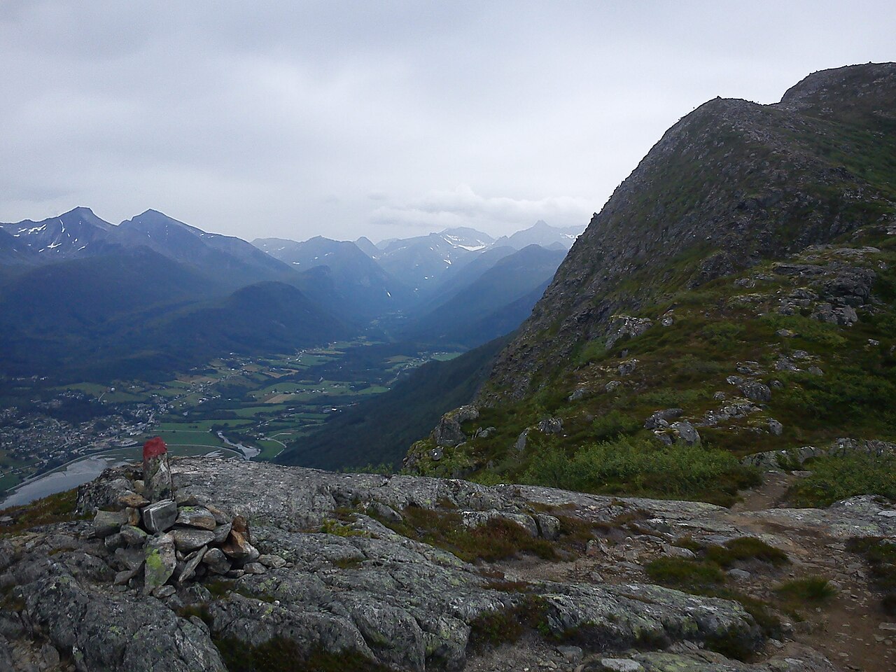 Cairn with a red T trail marker on the Romsdalseggen ridge, with Åndalsnes and Romsdalen far below