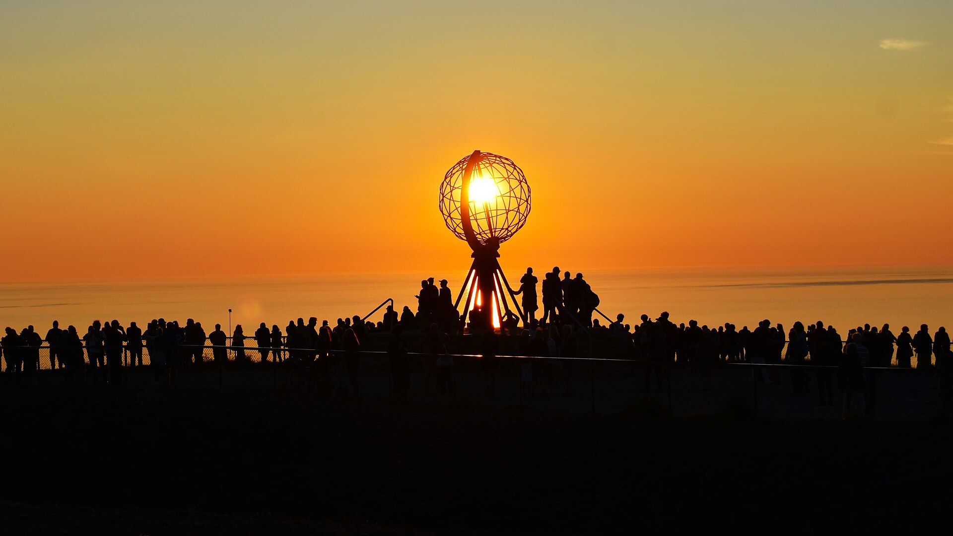 Midnight sun behind the globe monument at Nordkapp, the North Cape in Arctic Norway